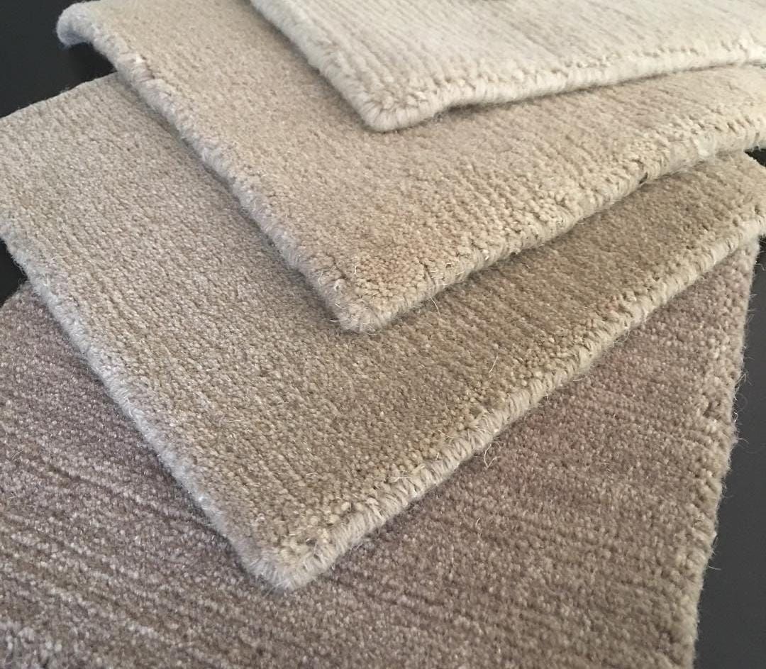 Stack of wool rug samples in natural beige and taupe
