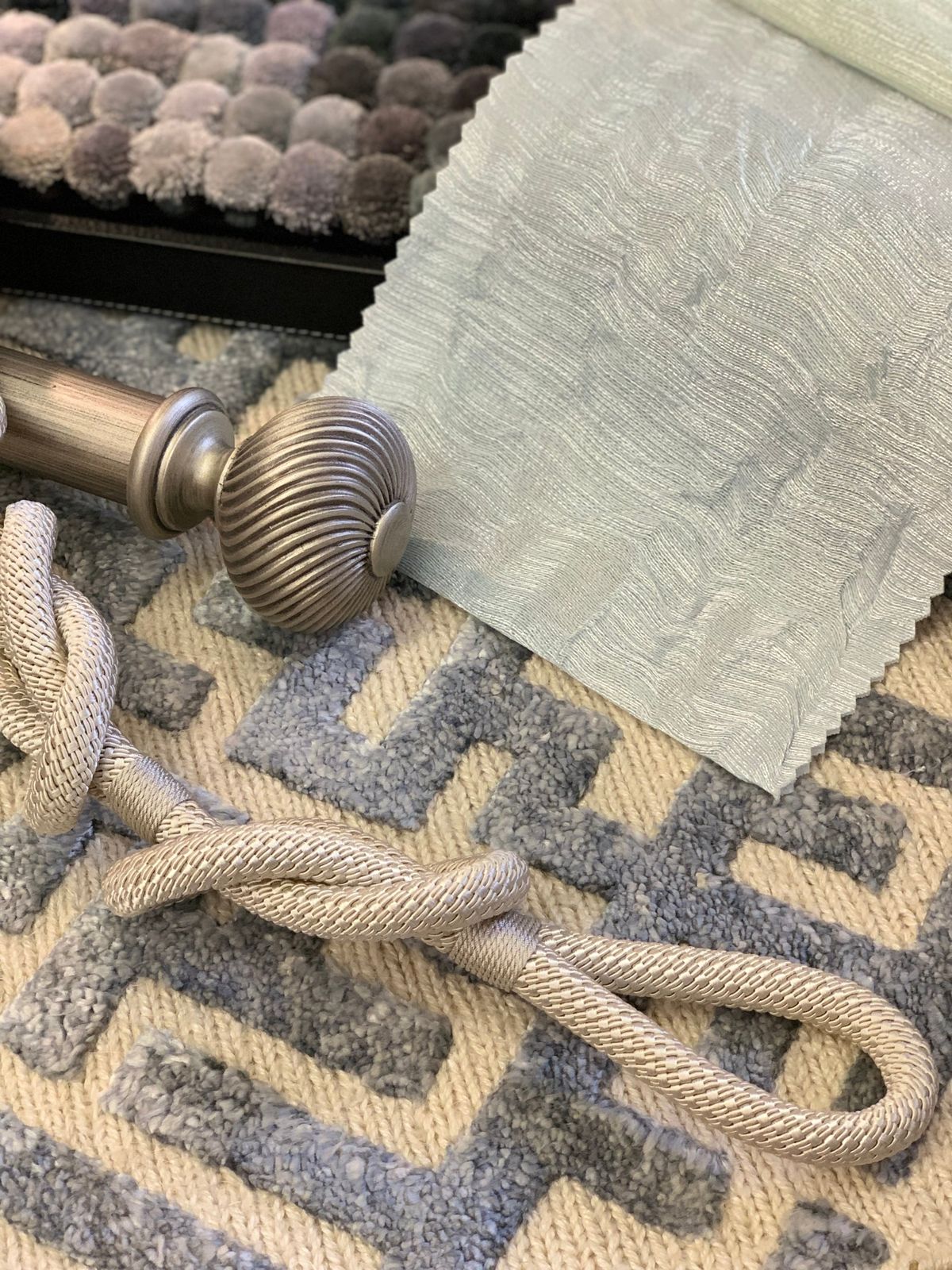 Blue and cream rug with a meander pattern, shown with a curtain fabric, tieback and curtain pole
