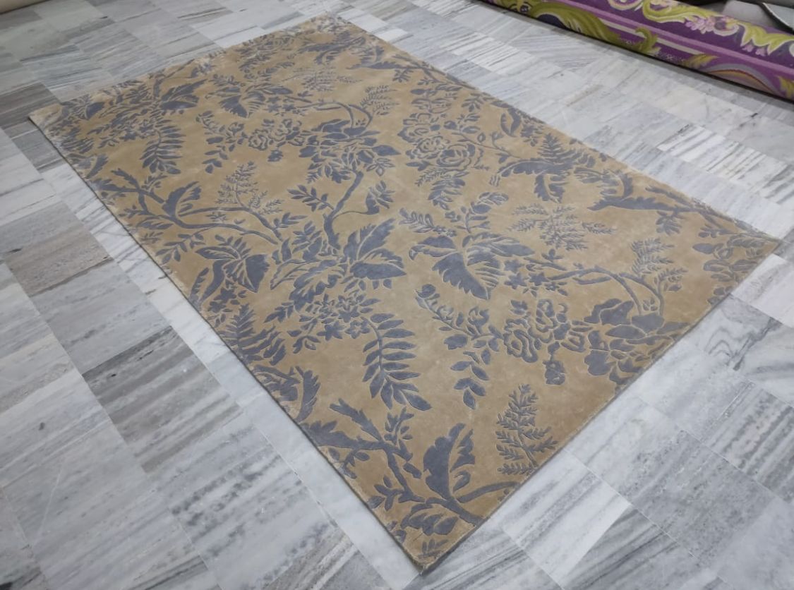 Finished rug with the same floral pattern in grey on a golden ground