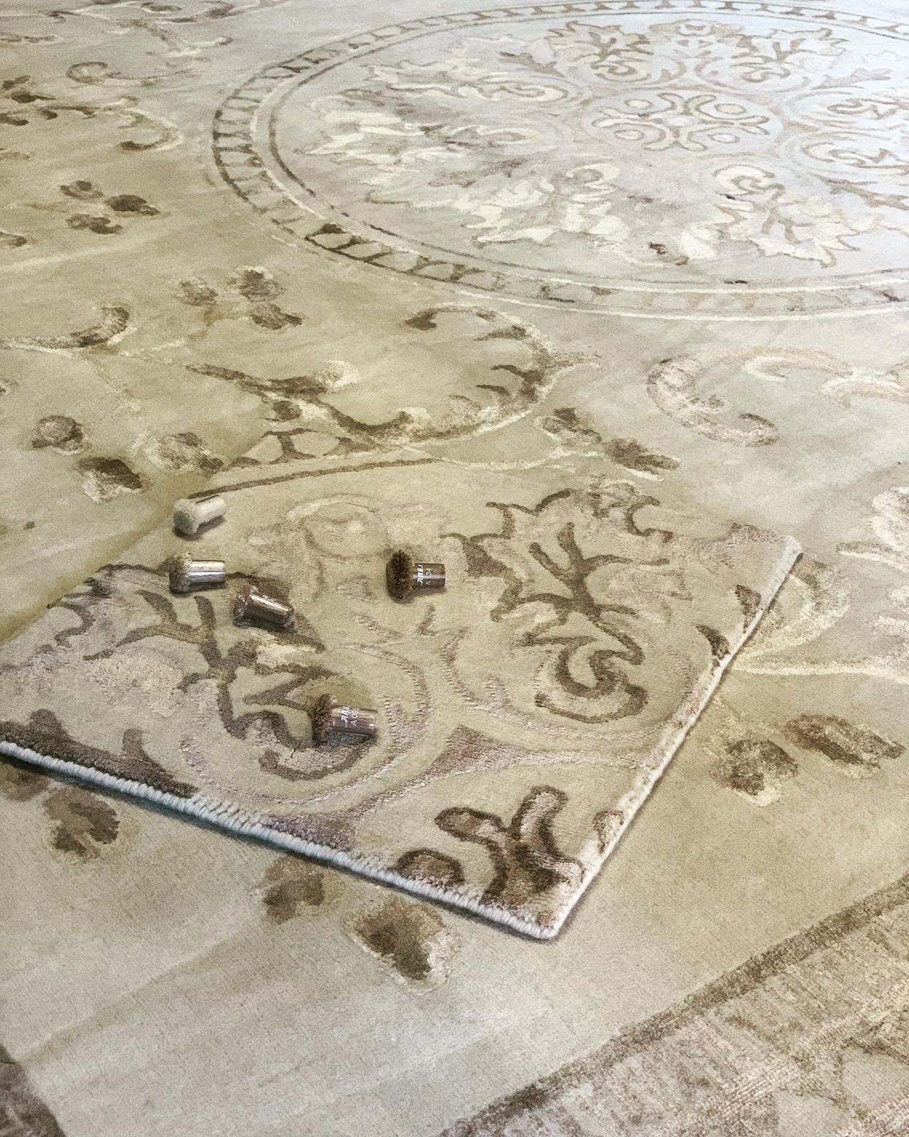 Large medallion rug in sand tones with a strike-off sample and colour poms laid on top